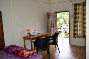 a room with a desk and chairs and a table and a door at Ha Lad in Mawlynnong