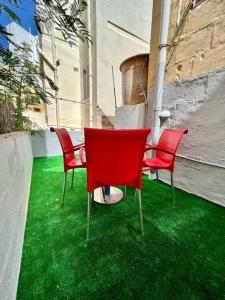 un groupe de chaises rouges assises sur un sol vert dans l'établissement Graswald, 1 bedroom accommodation, à Il-Gżira