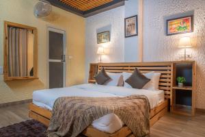 um quarto com uma cama grande com lençóis brancos e almofadas em Kasauli dream hills em Kasauli