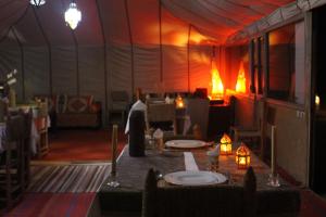 a tent with tables and chairs and a person in a room at Shooting Stars Camp in Merzouga