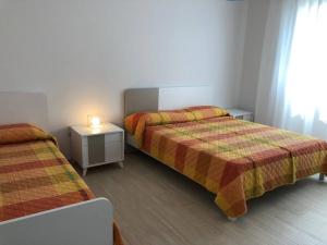 um quarto com 2 camas e uma mesa de cabeceira com um candeeiro em FAMILY APARTMENT VI20 - Piazza Brescia - Adria Holiday Jesolo em Lido di Jesolo