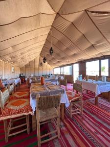 a large tent with tables and chairs in it at Shooting Stars Camp in Merzouga