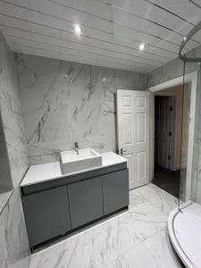 a bathroom with a sink and a white marble wall at OYO The Pleasant House in Manchester