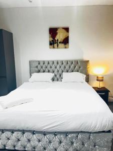 a bedroom with a large white bed with a headboard at OYO The Pleasant House in Manchester