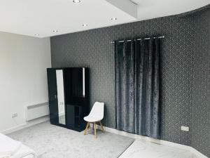 a bedroom with a white chair and a black wall at OYO The Pleasant House in Manchester