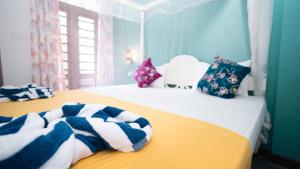 two beds with towels on them in a bedroom at Daffodil Restaurant & Holiday Resort in Unawatuna