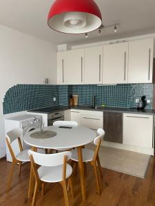 une cuisine avec une table et des chaises blanches et une lumière rouge dans l'établissement Neon Gondola apartment, à Bansko 5 autres photos