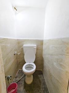 a bathroom with a toilet and a red bucket at Shivay homestay ujjain in Ujjain