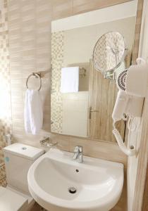 ein Badezimmer mit einem weißen Waschbecken und einem Spiegel in der Unterkunft La Riva Hotel in Aqaba