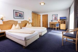 ein Hotelzimmer mit 2 Betten und einem Schreibtisch in der Unterkunft Allgäuer Bergbad in Oberstdorf