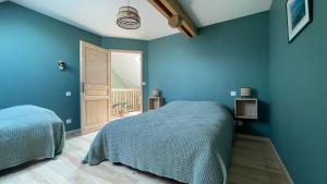a blue bedroom with two beds and a door at Gîte des Pierres de Barme in Olby