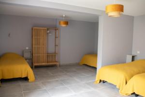 2 Betten in einem Zimmer mit gelben Decken darauf in der Unterkunft Gîte des Pierres de Barme in Olby