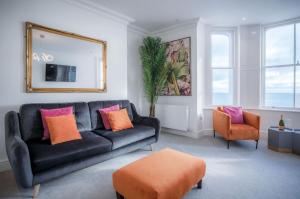 a living room with a black couch and orange and pink pillows at Caldey View - Luxury 2 Bedroom - Panorama - Tenby in Tenby