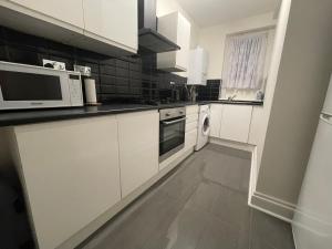 a kitchen with white cabinets and white appliances at Homely and very comfortable apartment in London