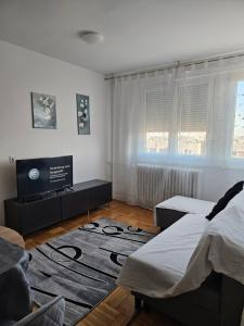 a bedroom with two beds and a flat screen tv at Apartman FITT in Zagreb