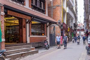 eine Gruppe von Menschen, die vor einem Geschäft die Straße hinuntergehen in der Unterkunft Darbar Heritage Inn in Kathmandu