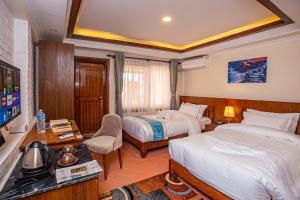 um quarto de hotel com duas camas e uma televisão em Darbar Heritage Inn em Kathmandu