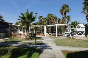 a park with a playground with a swing at Giardini Sausari Residence in Punta Prosciutto