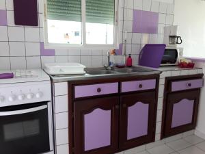 a kitchen with purple cabinets and a sink at Appartements: plage & commerces à 200m in Sainte-Anne