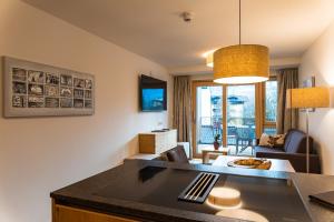 湖畔捷爾的住宿－Spa Apartments - Zell am See，厨房以及带沙发和桌子的客厅。