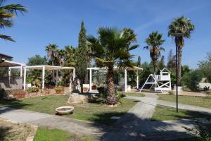 a park with palm trees and a swing at Giardini Sausari Residence in Punta Prosciutto