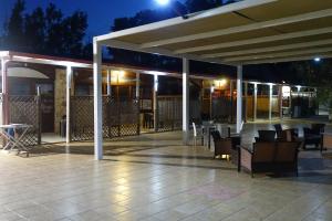 a patio with tables and chairs under a pavilion at night at Giardini Sausari Residence in Punta Prosciutto