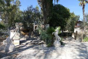 a garden with statues of cats and palm trees at Giardini Sausari Residence in Punta Prosciutto
