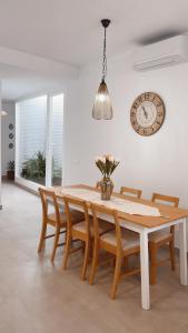 mesa de comedor con sillas y reloj en la pared en El Paseo, en Belmonte