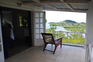a chair on a porch with a view of a river at Villa Palissandre in Nosy Be