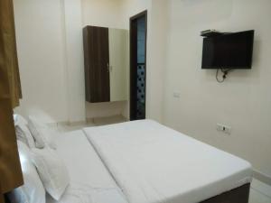 a white room with a bed and a flat screen tv at Kesari root in Amritsar