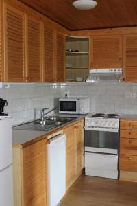 uma cozinha com electrodomésticos brancos e armários de madeira em Chill Cave - logwood cottage em Ruka
