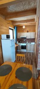 a kitchen with a table and a white refrigerator at Domek pod Lipą in Korbielów