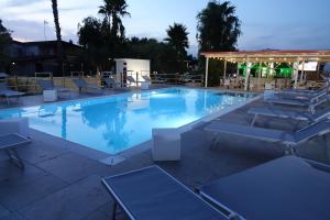 a large swimming pool with chairs and a pavilion at Giardini Sausari Residence in Punta Prosciutto