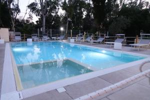 a large swimming pool with chairs and a table at Giardini Sausari Residence in Punta Prosciutto