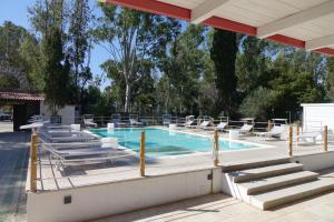 a swimming pool with lounge chairs and a swimming pool at Giardini Sausari Residence in Punta Prosciutto