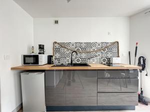 a kitchen with a counter with a sink and a microwave at Breizh Appart in Morlaix