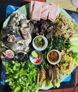 un plato de comida con marisco y verduras en una mesa en Nung Gia Homestay, en Xin Man