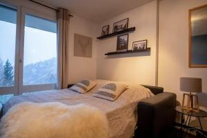 a bedroom with a bed and a large window at Studio Maona - skis au pied in LʼHuez