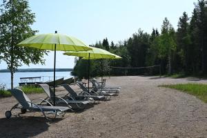 a row of chairs and umbrellas on a beach at Rukajärven Lomamajat Cottage 3 in Kuusamo