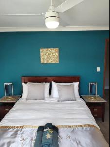 a bedroom with a large bed with a blue wall at Three Palms in Kooralbyn