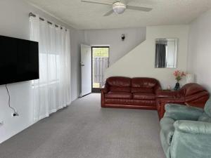 a living room with a couch and a flat screen tv at A Beach front Apartment in Batehaven