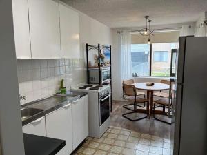 a kitchen with white cabinets and a table with a dining room at A Beach front Apartment in Batehaven
