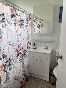 a bathroom with a shower curtain with a sink at A Beach front Apartment in Batehaven