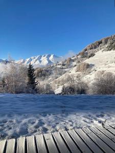 un campo cubierto de nieve con montañas al fondo en Studio Maona - skis au pied en Huez