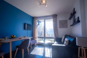 Sala de estar azul con mesa y sofá en Studio Maona - skis au pied en Huez