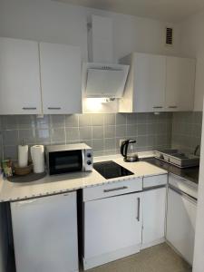 eine kleine Küche mit weißen Schränken und einer Mikrowelle in der Unterkunft Stay-Happy Flat in Halstenbek in Halstenbek