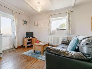 a living room with a leather couch and a table at 1 Bed in Sennen CLOPC in St Just