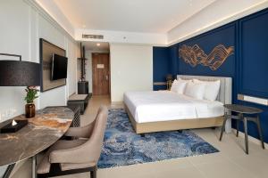 a bedroom with a king sized bed and a desk at The Sentra Manado in Manado