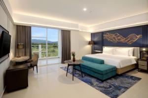 a bedroom with a bed and a desk and a television at The Sentra Manado in Manado