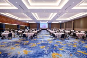a banquet hall with tables and chairs and a projection screen at The Sentra Manado in Manado